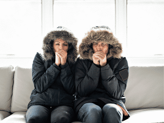 couple sitting on couch wearing winter jackets because they need heating repair in Shreveport