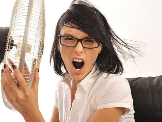 angry woman in front of fan because ac isn't working