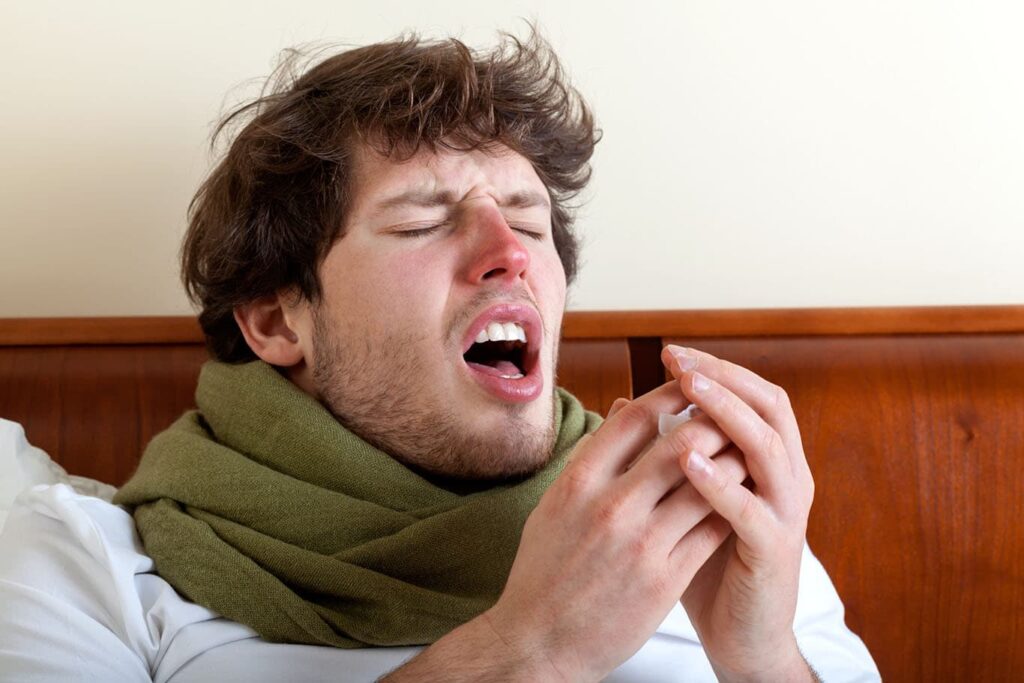 man sneezing due to allergies